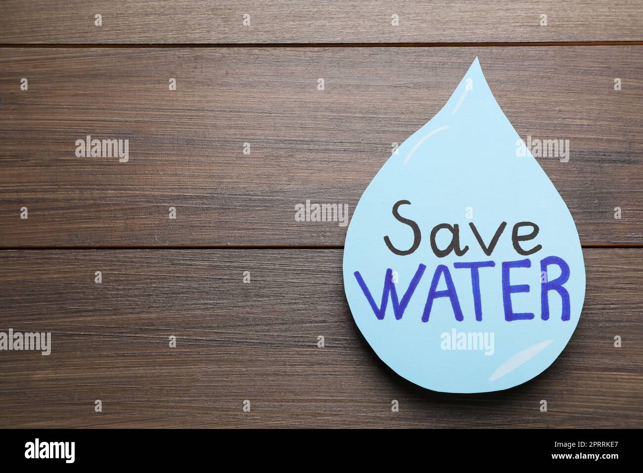 Paper drop with words Save Water on wooden table, top view. Space for