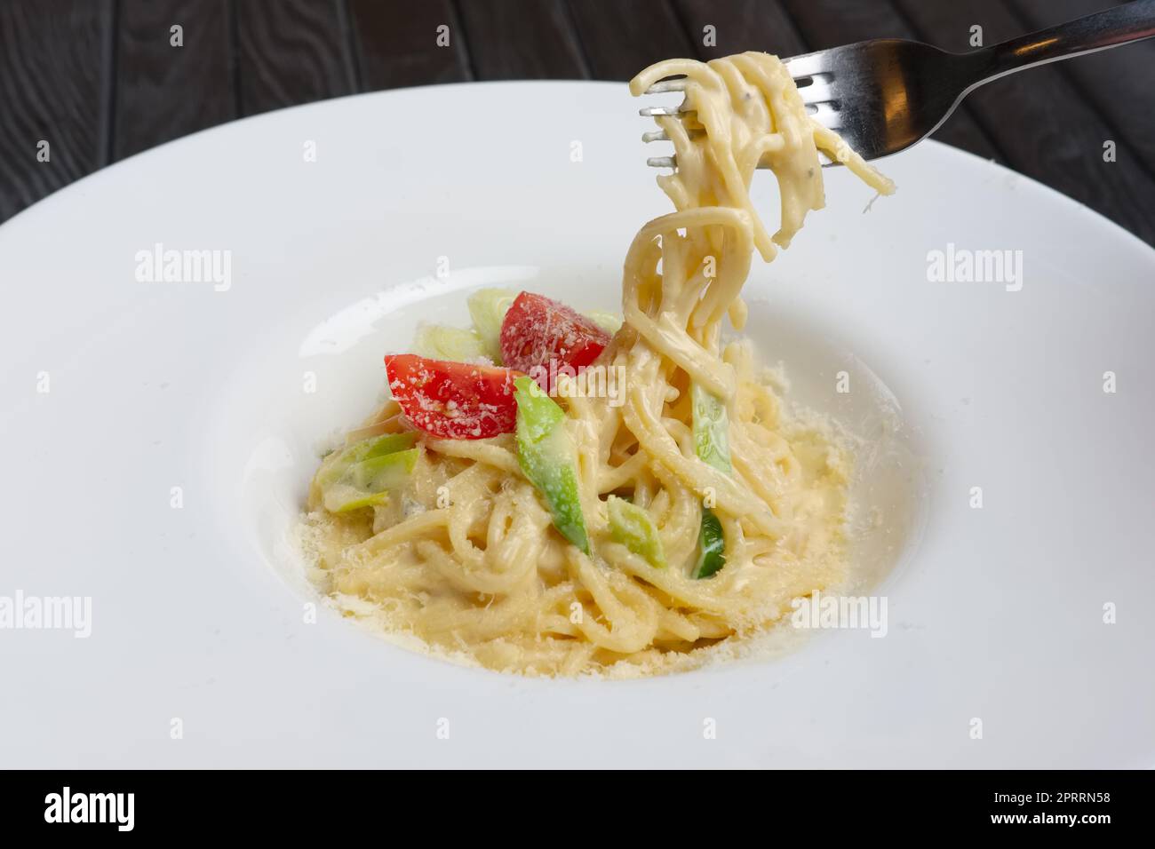 Plate with pasta served with bacon and ham with tomato cherry Stock Photo