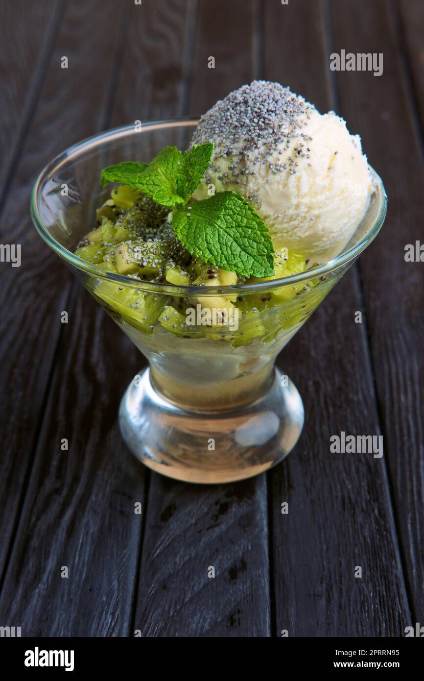 A cup of apple ice cream decorated with kiwi, mint leaves and poppy Stock Photo