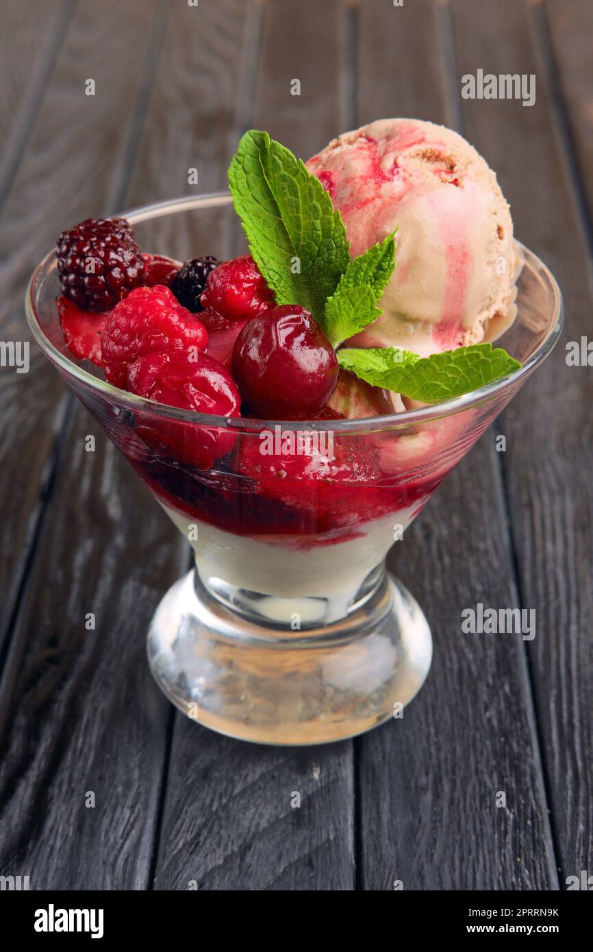 A cup of cherry ice cream decorated with raspberries and dewberry and mint leaves Stock Photo