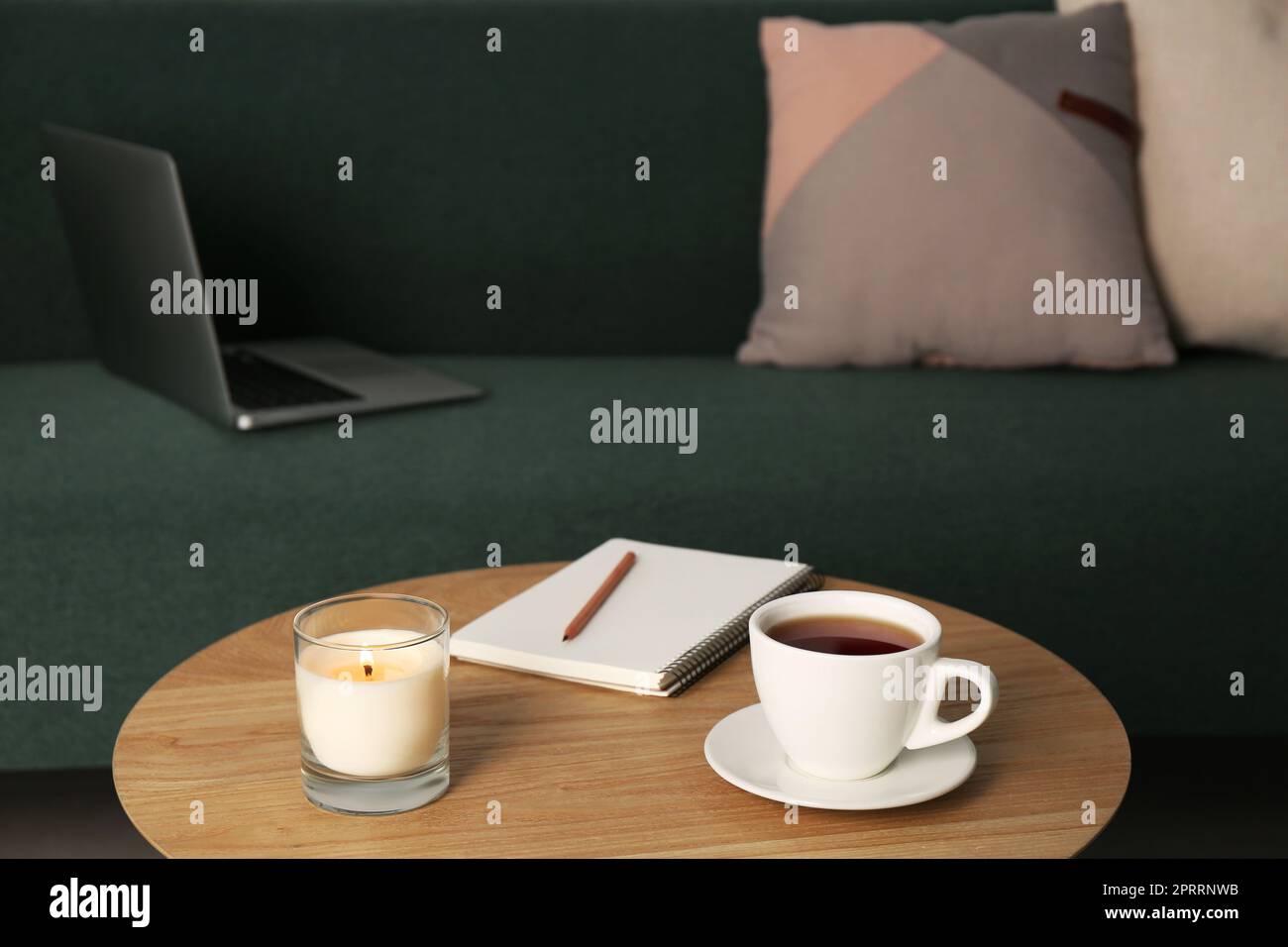 Wooden side table near sofa with laptop in room. Interior design Stock