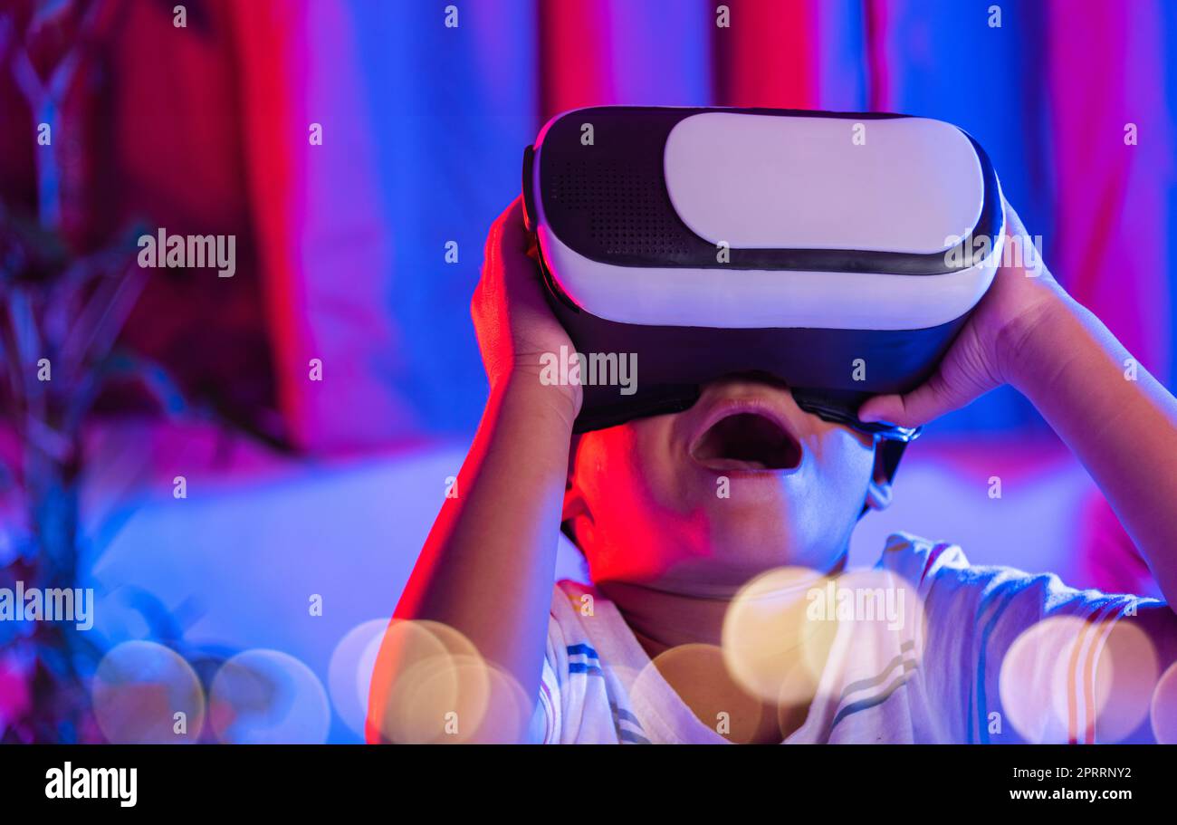 Asian little kid boy wearing virtual reality goggles experiencing reality Stock Photo