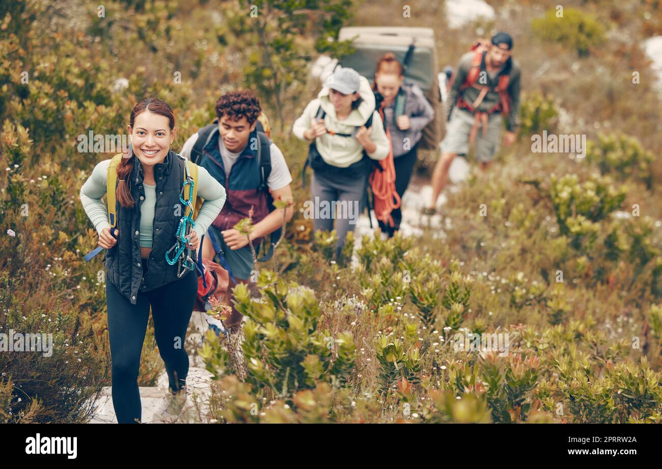 Group of friends hike trail up mountain, to camp in nature landscape on extreme adventure holiday. Team of people explore earth together, on hiking trip to mountains or hill while on vacation. Stock Photo