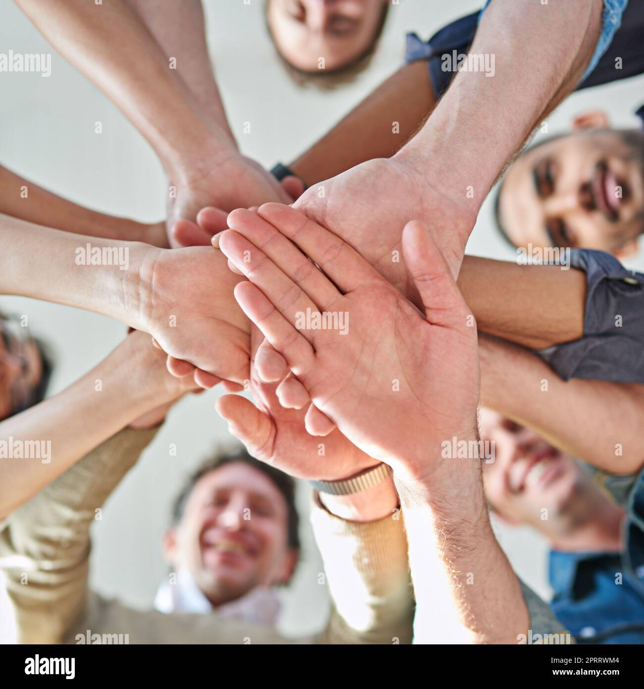 Teamwork divides the task and multiplies the success. Low angle shot of a group of co-workers stacking their hands on top of each other. Stock Photo