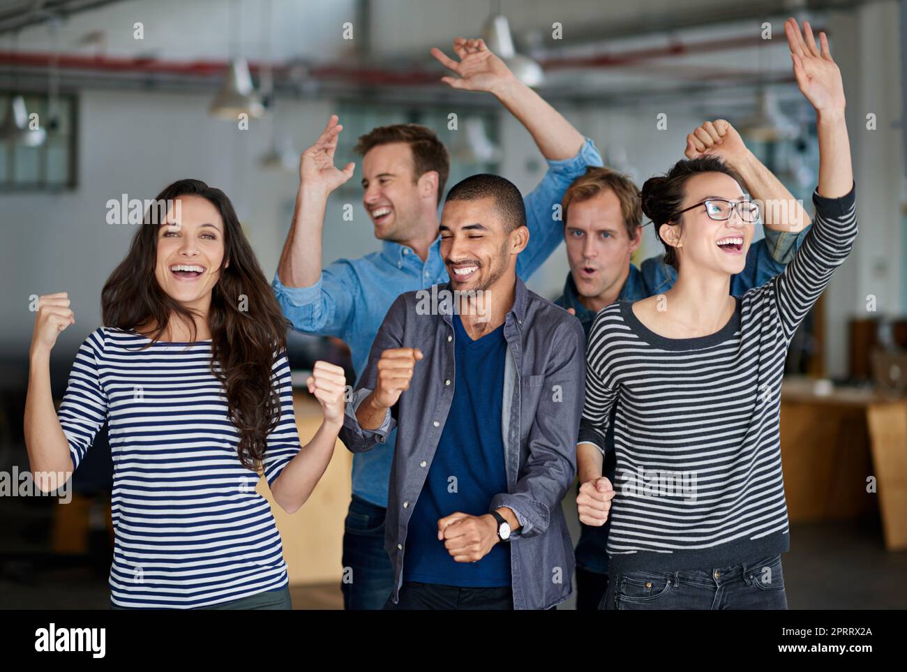 Time to party. Group of office staff shouting and dancing together in their office. Stock Photo