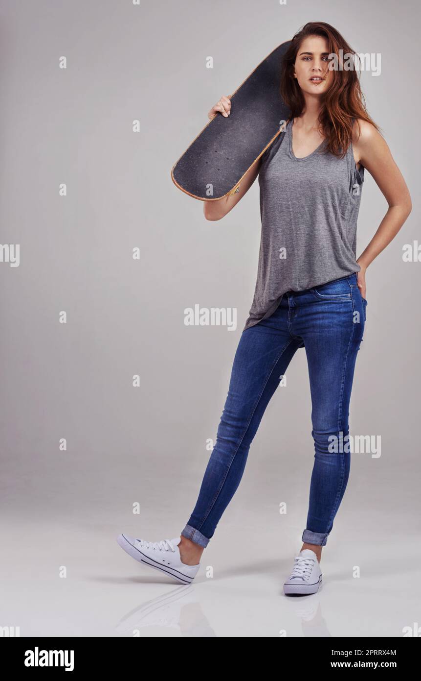 Skateboarding isnt a hobby, its a lifestyle. Full length studio portrait of casually-dressed young woman holding on a skateboard. Stock Photo
