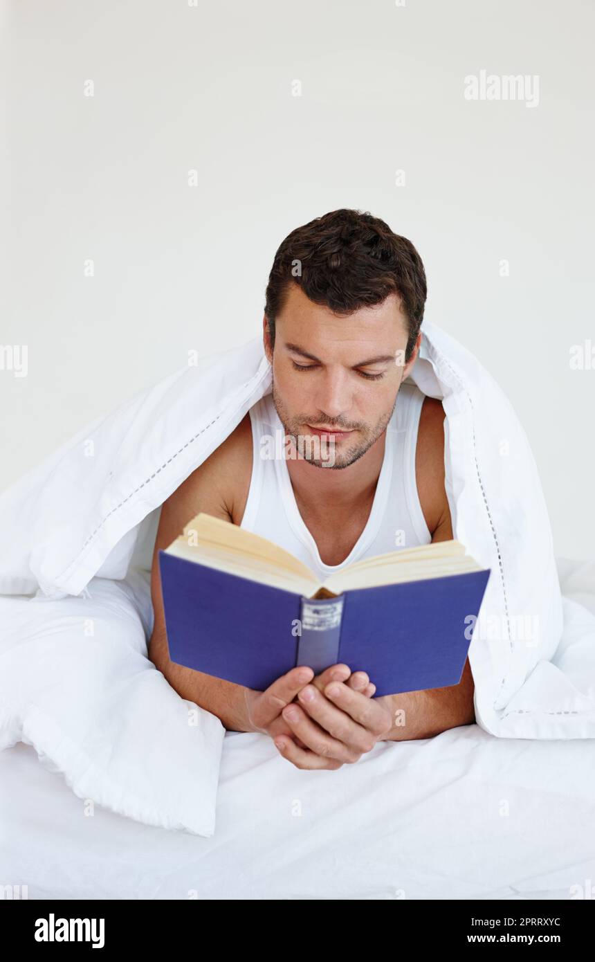 Lost in the world of literature. A man lying comfortably in his bed