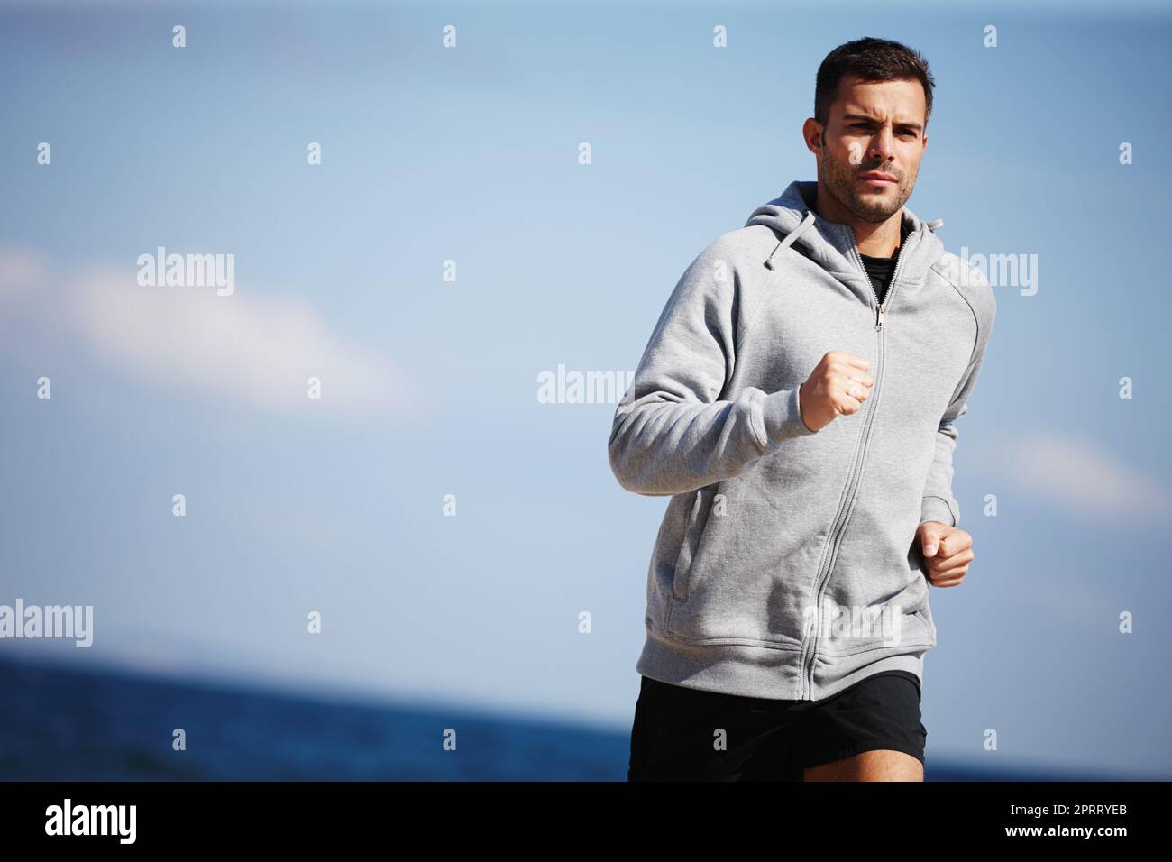 Jogging near the ocean. a handsome young man running on the beach. Stock Photo