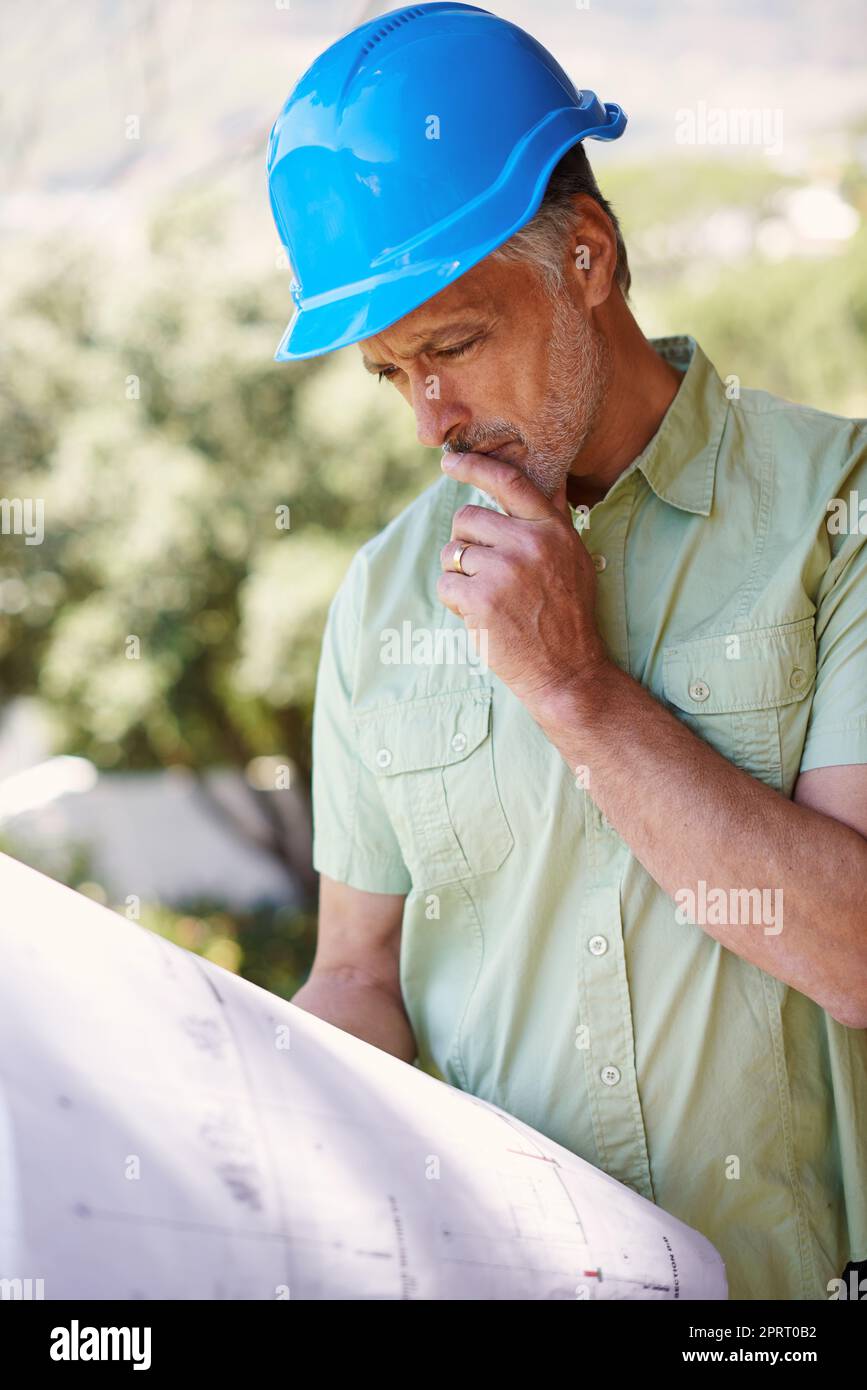 Making sure that the plans are being adhered to. a building contractor looking at plans. Stock Photo