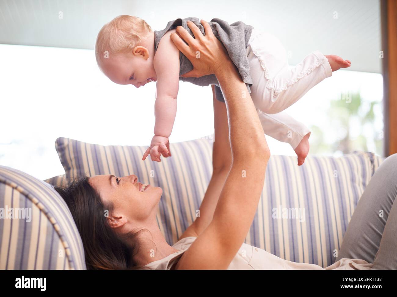 Raising him right. an attractive young woman playing with her baby girl on the sofa. Stock Photo