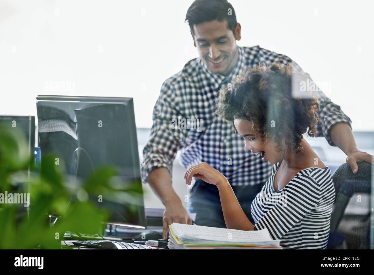 Giving her the good news. two young designers working on a pc. Stock Photo