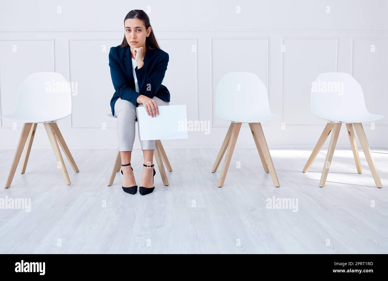 Portrait business woman waiting for an interview or stress applicant sitting alone. Sad or nervous corporate professional holding resume in line for job opening, vacancy and opportunity in office Stock Photo