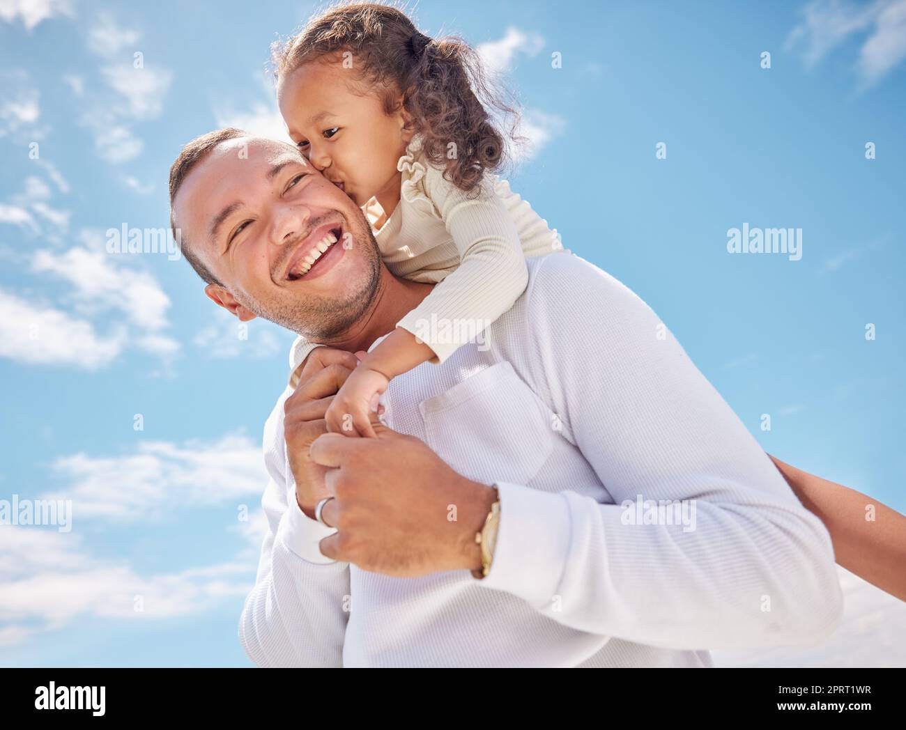 Girl child kiss dad with love, smile and care playing together on summer day with sunny blue sky outdoor. Happy smiling family man or father with beautiful Asian baby girl hug have fun and happiness Stock Photo