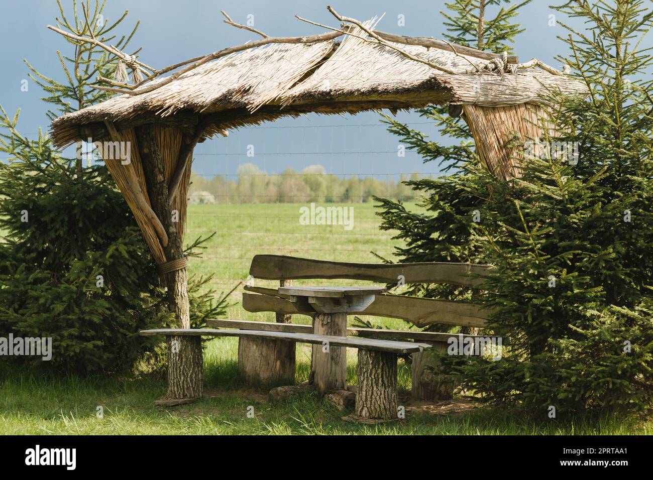 An old wooden gazebo for relaxing in the park. Equipped with wooden tables and benches. Stock Photo