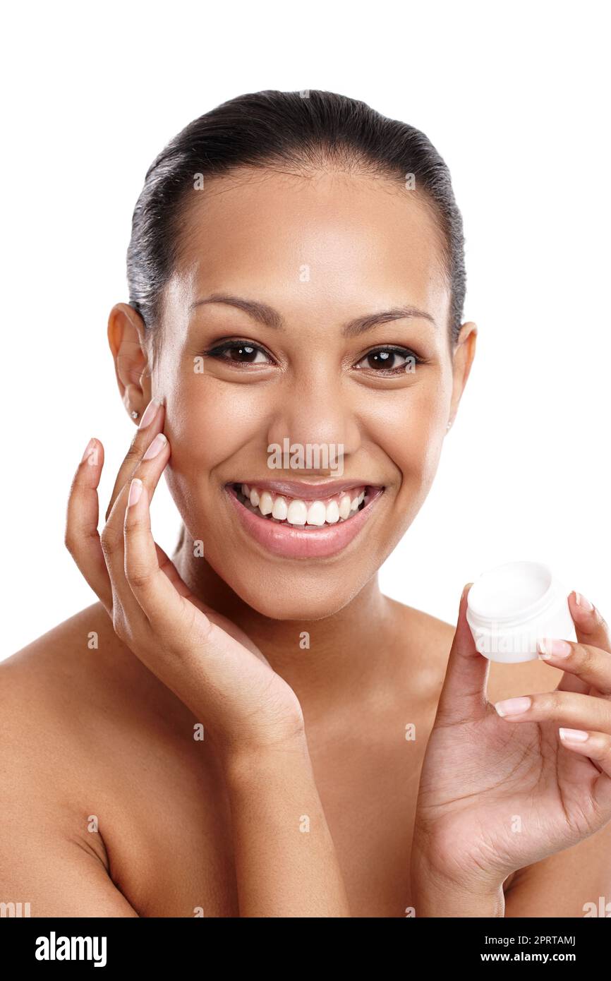 Beauty rule number 1 Always moisturize. a beautiful young woman applying face cream while standing in a studio. Stock Photo