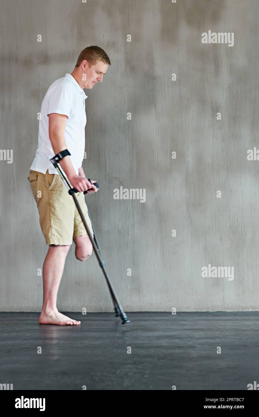 Stepping out. an young man with one leg walking on crutches in a