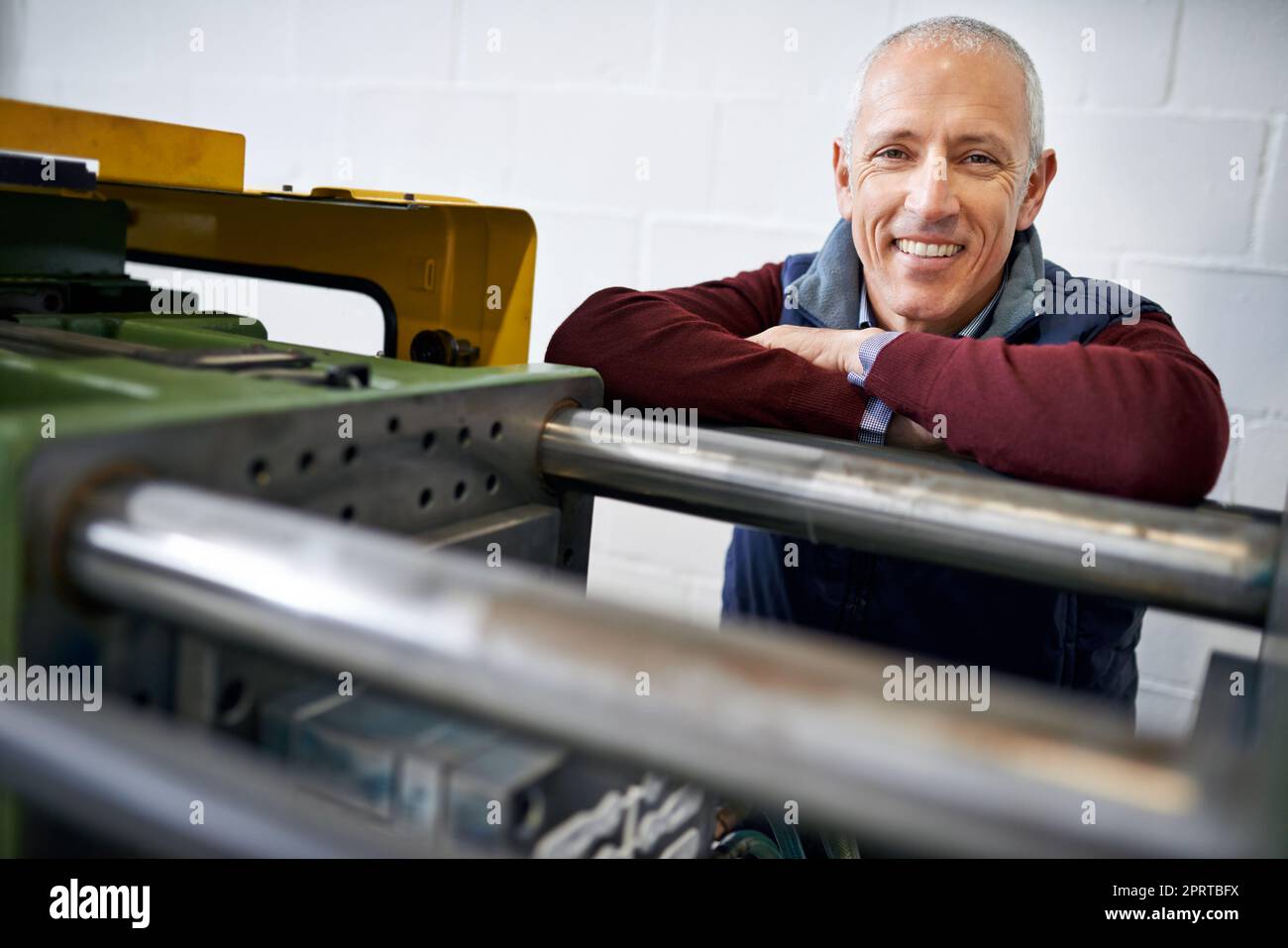 Everything is in perfect working order. Portrait of a mature man standing next to machinery in a factory. Stock Photo