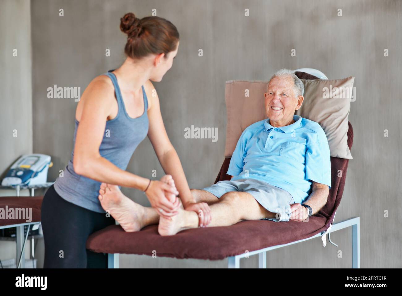Helping her patients stay strong and healthy. a a physical therapist working with a senior man. Stock Photo