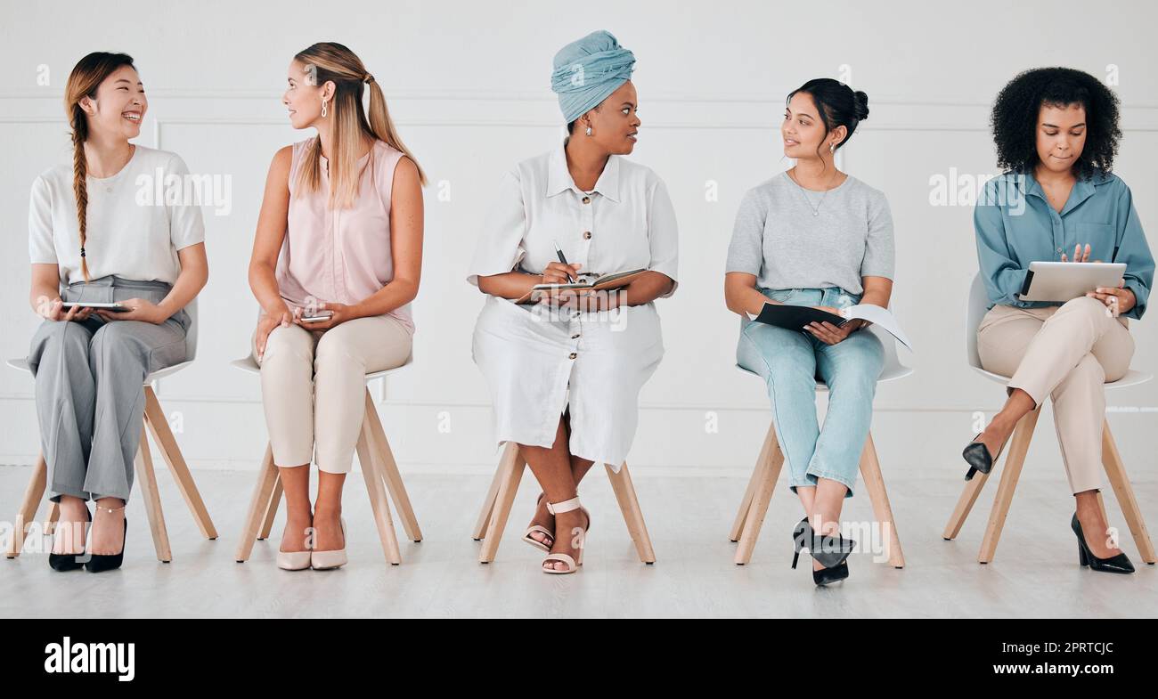 Diversity, interview and business people in waiting room at a job, hiring or recruitment center. Corporate, women and professionals talking with technology in a unemployment office for a work vacancy Stock Photo