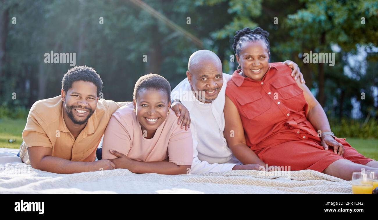Family picnic, park portrait and happy parents with children in summer, happiness in nature garden together and smile for relax in spring. Black woman and black man with young people in countryside Stock Photo