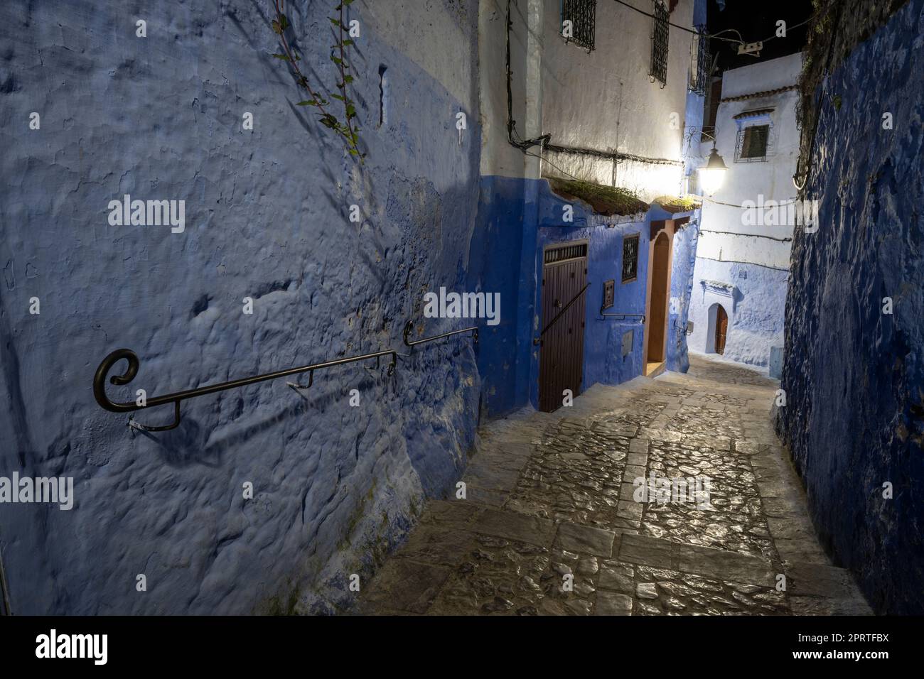 Alley in the town of Chefchaouen illuminated by the artificial light of street lamps. Stock Photo
