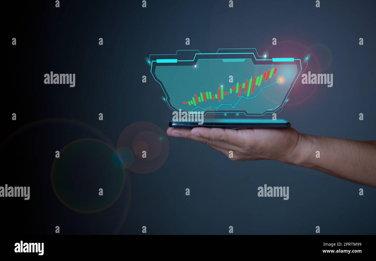 Hologram image of a candlestick chart from a phone on a person's hand. Offer trading, investment ideas Stock Photo