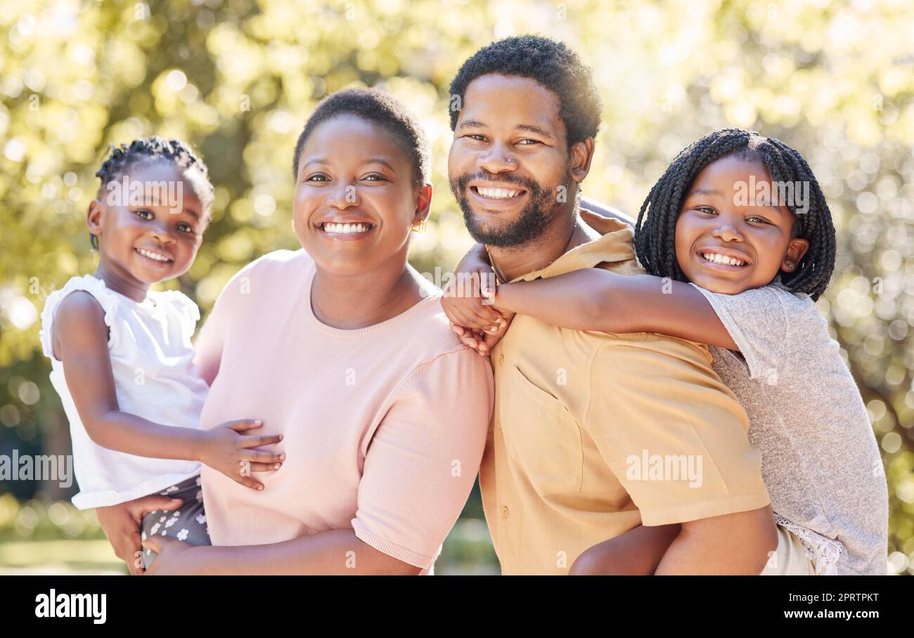 Children, family and love with a black man, woman and their kids outdoor in the park during summer. Happy, smile and parents with a mother, father and daughters as sister siblings outside together Stock Photo