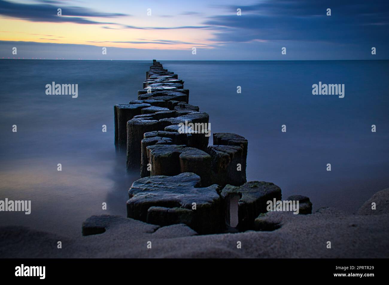 Groynes protruding into the horizon in the Baltic Sea. Long exposure with muted colors Stock Photo