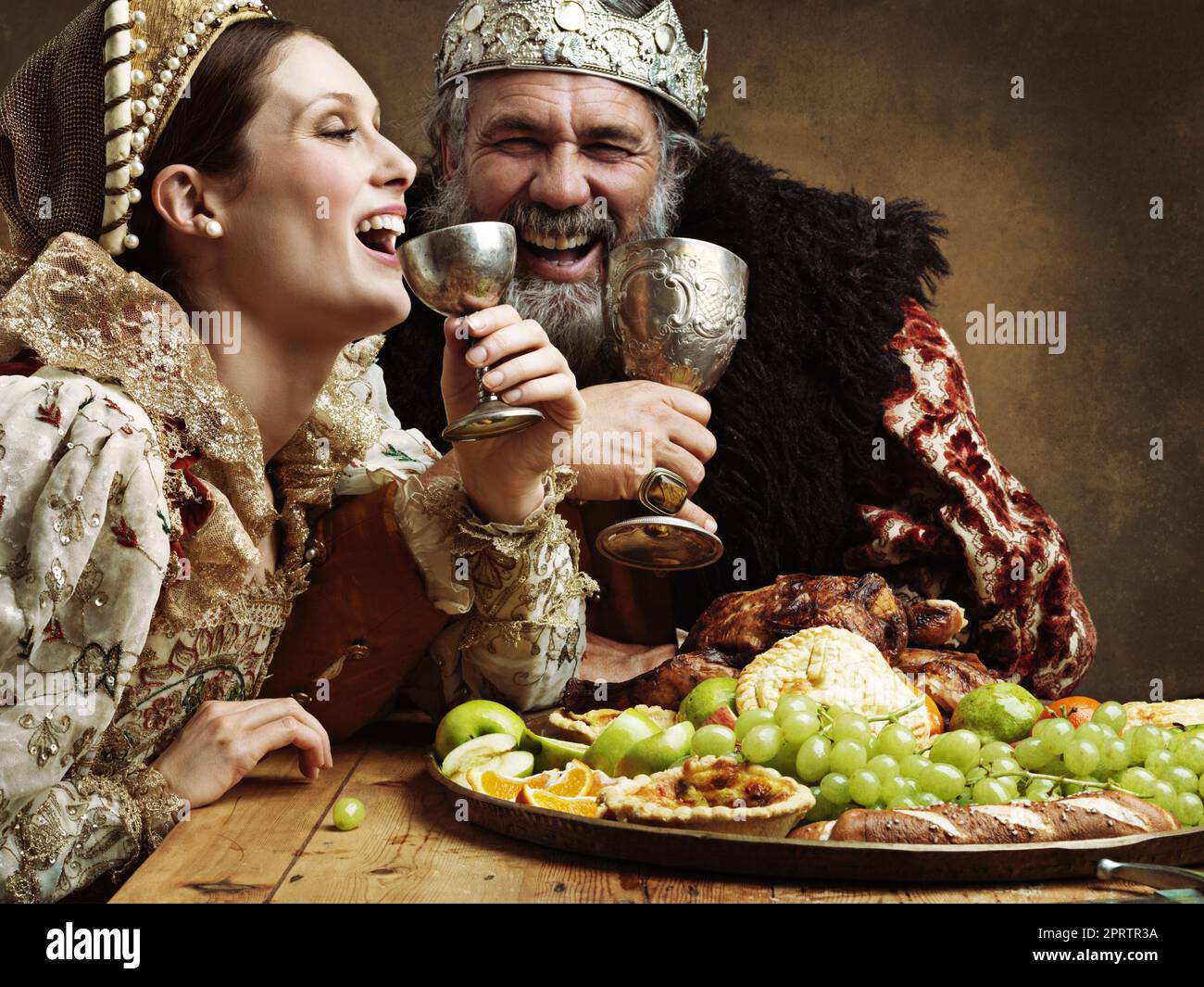 Mead and merriment. A mature king feasting alone in a banquet hall. Stock Photo