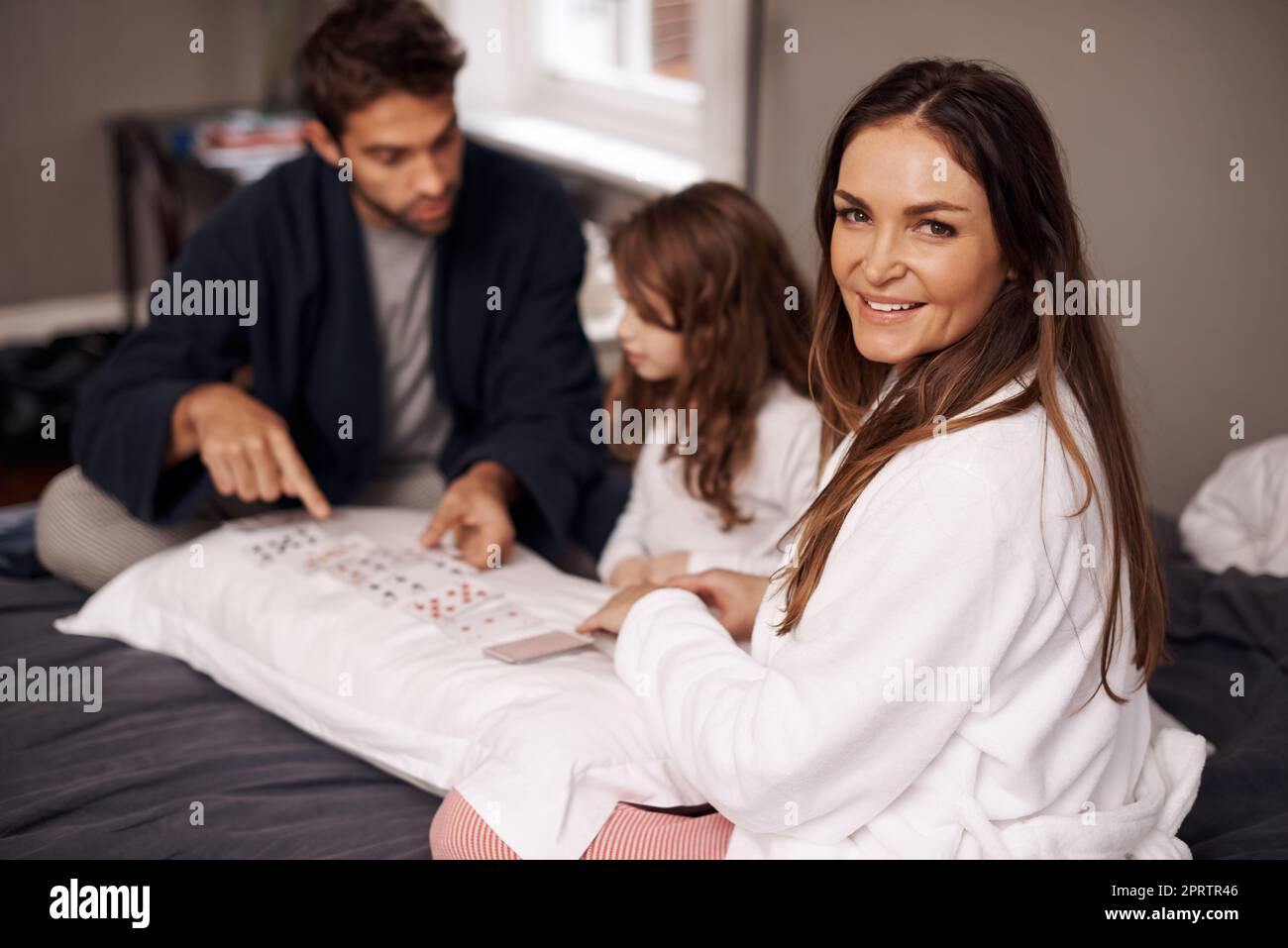 They love their card games. a young family playing cards together at home. Stock Photo