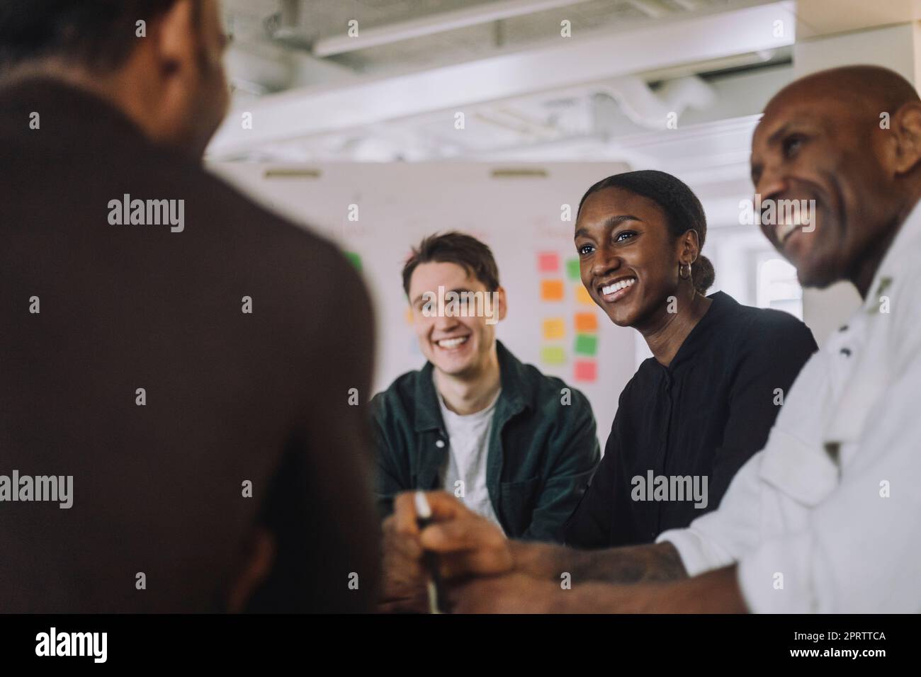 Happy students and male professor sitting in innovation lab Stock Photo