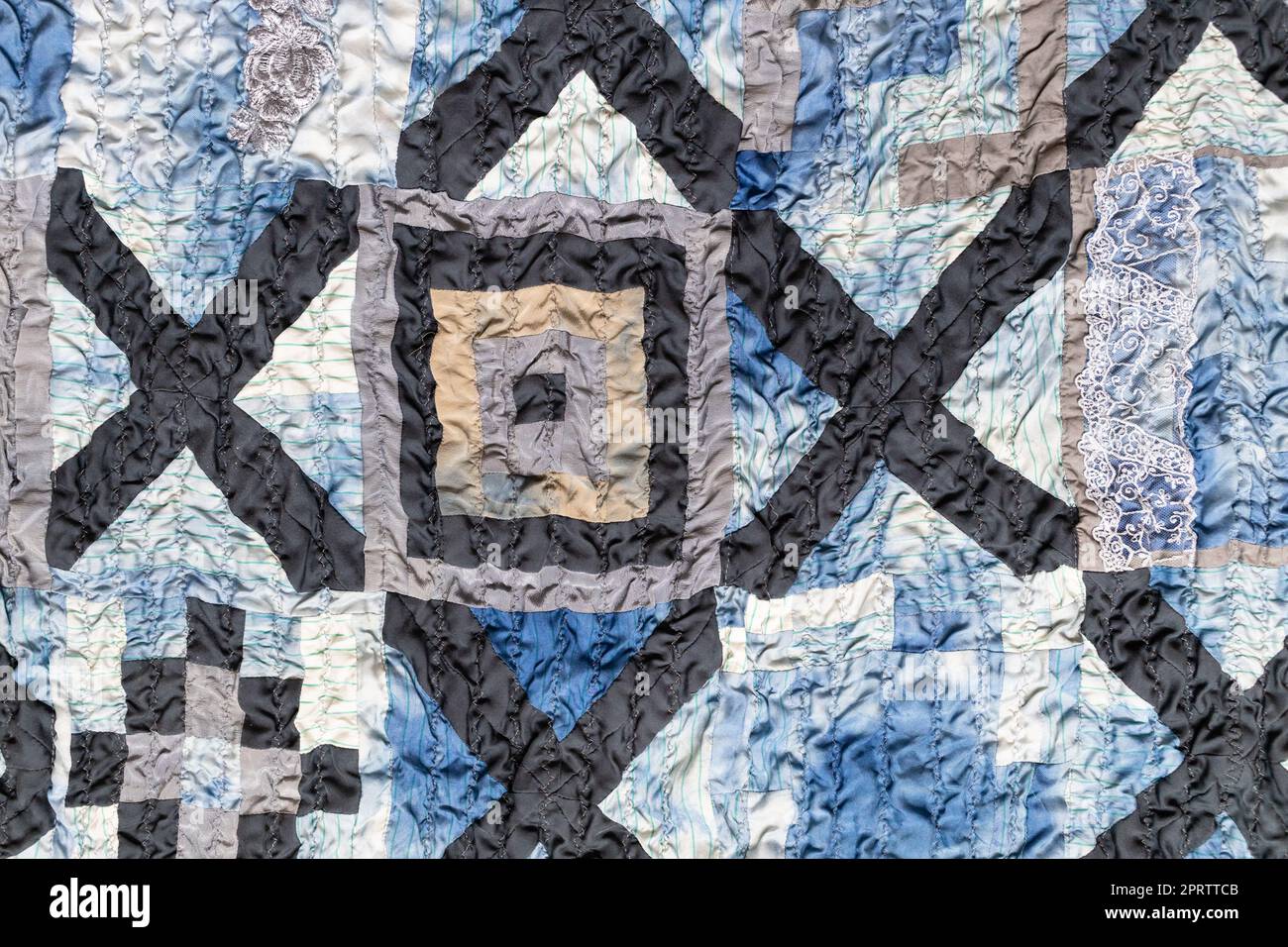 part of wrinkled hand-stitched patchwork quilt from pieces of various ...