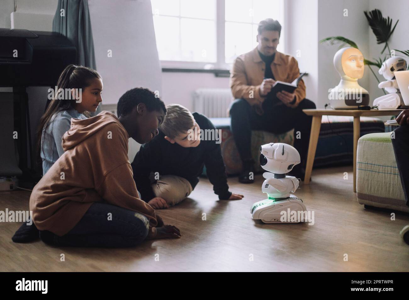 Multiracial students sitting in front of modern robot in innovation lab Stock Photo