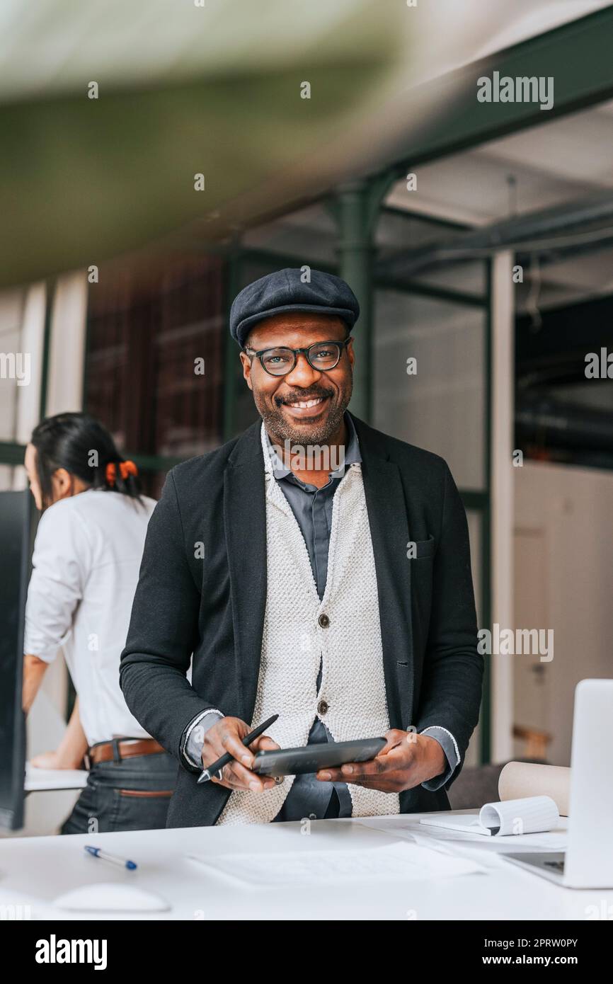 Smiling mature businessman holding tablet PC at office Stock Photo