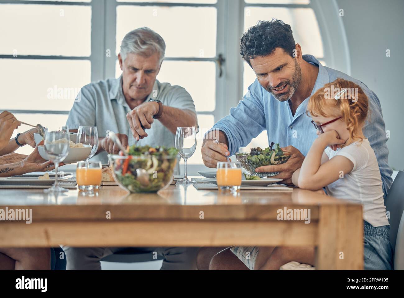 Dinner, family and child eating food at dining room table together at
