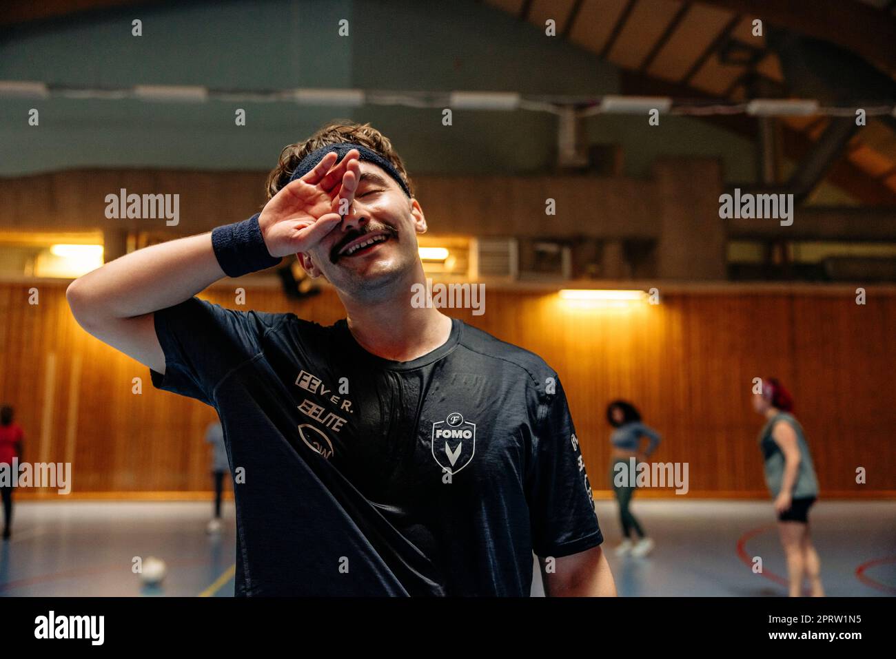 Smiling male athlete rubbing eye at sports court Stock Photo