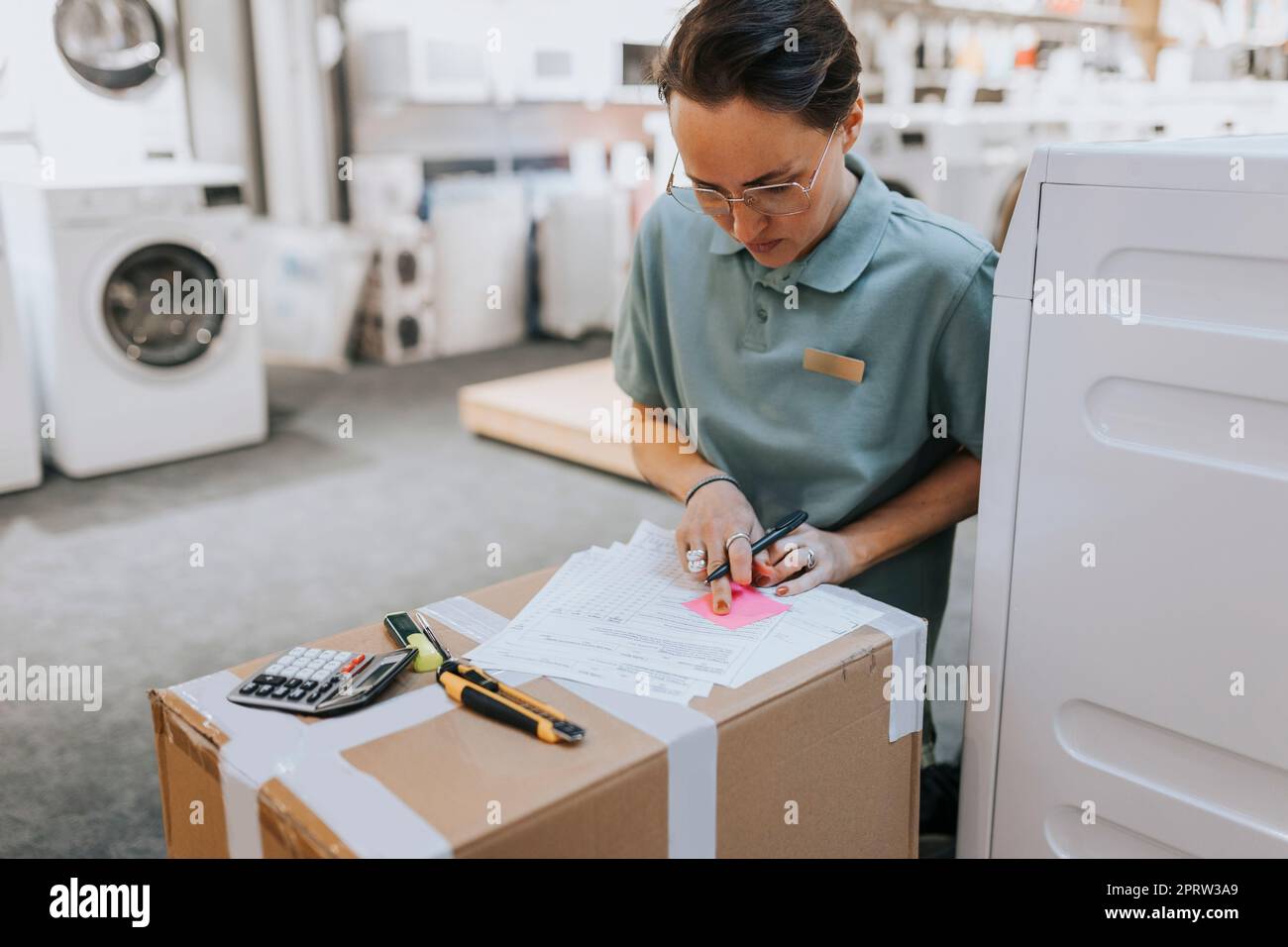 Female sales clerk doing paperwork while working in appliances store Stock Photo