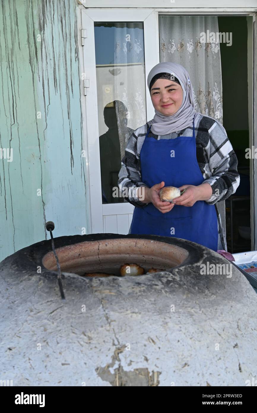 Uzbek woman cooking somsa, a traditional local snack, in a tandir oven in Bukhara, Uzbekistan Stock Photo