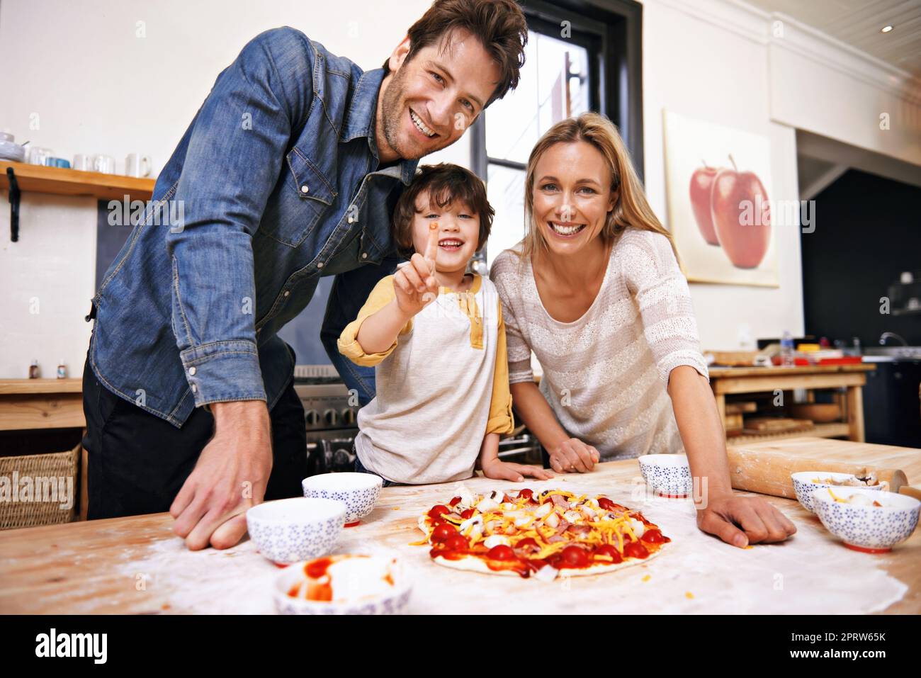 Homemade pizza beats takeaways every time. A family making pizza together at home. Stock Photo