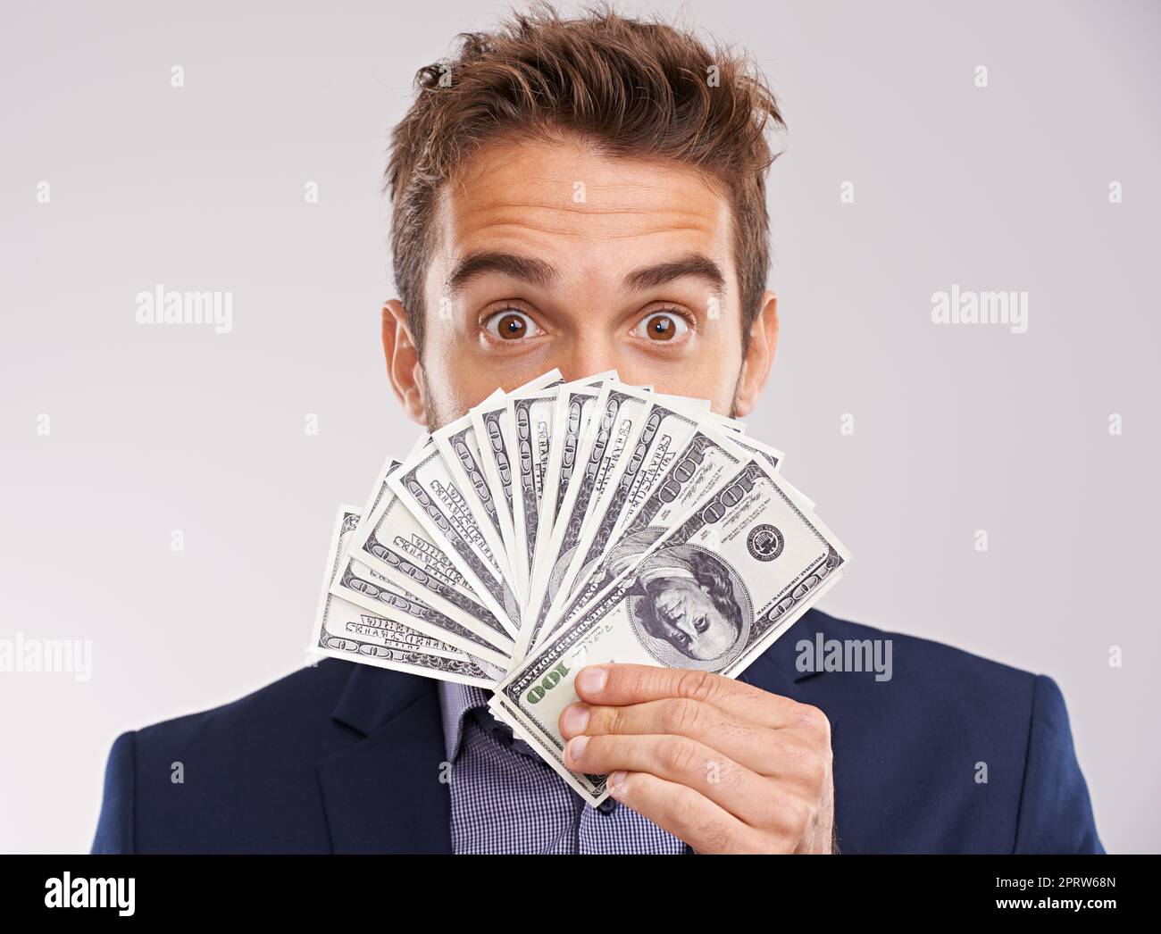 Show me the money. Studio shot of a businessman holding a fan of money in front of his face. Stock Photo