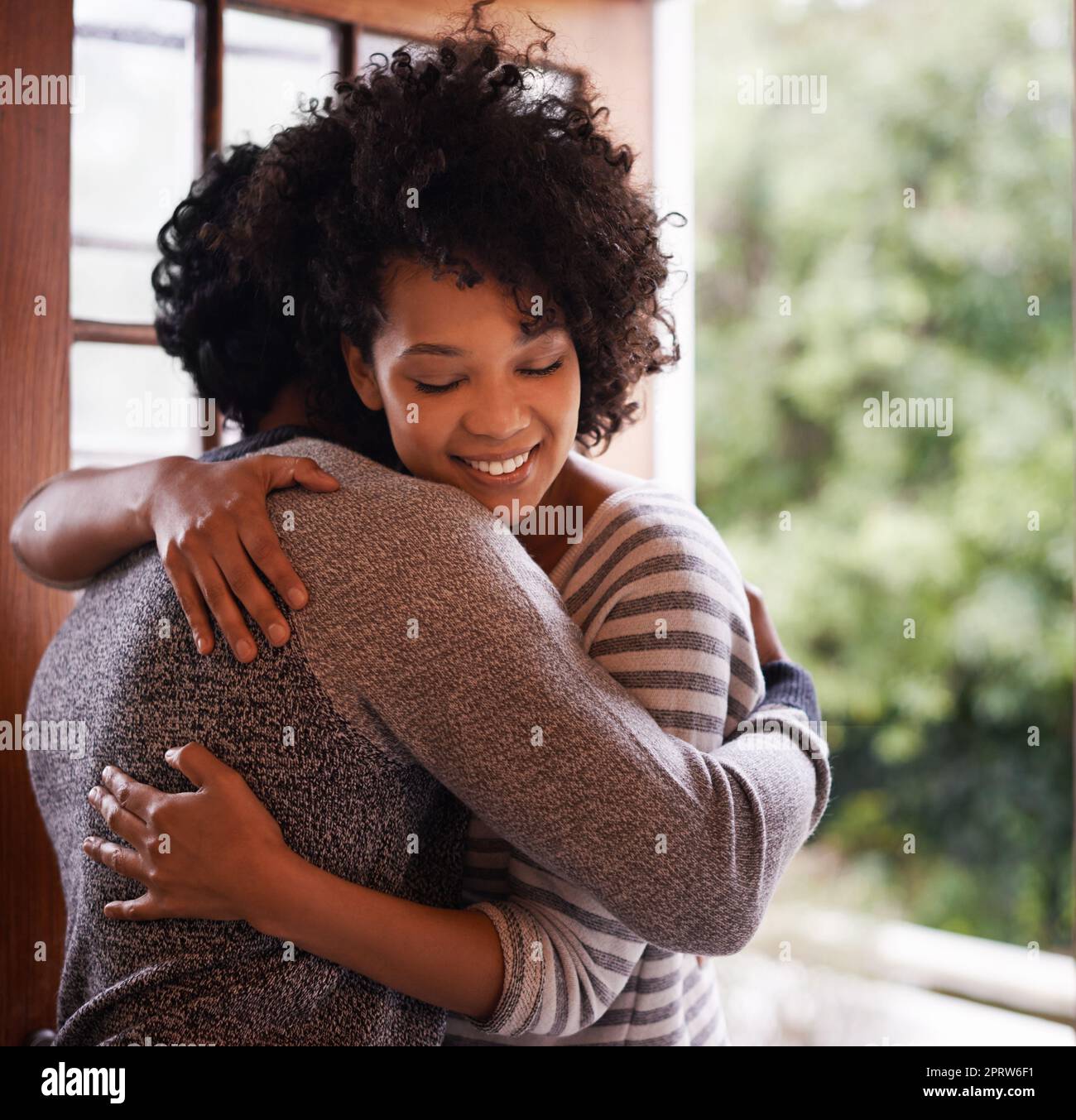 Greeting her with a warm embrace. a young woman greeting her husband at the door. Stock Photo