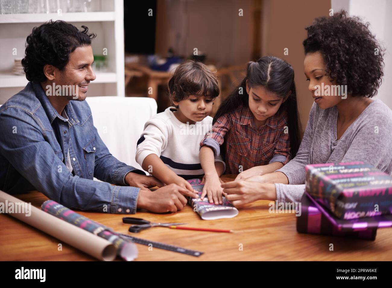 Wrapping all the goodies. A young family wrapping gifts at home. Stock Photo