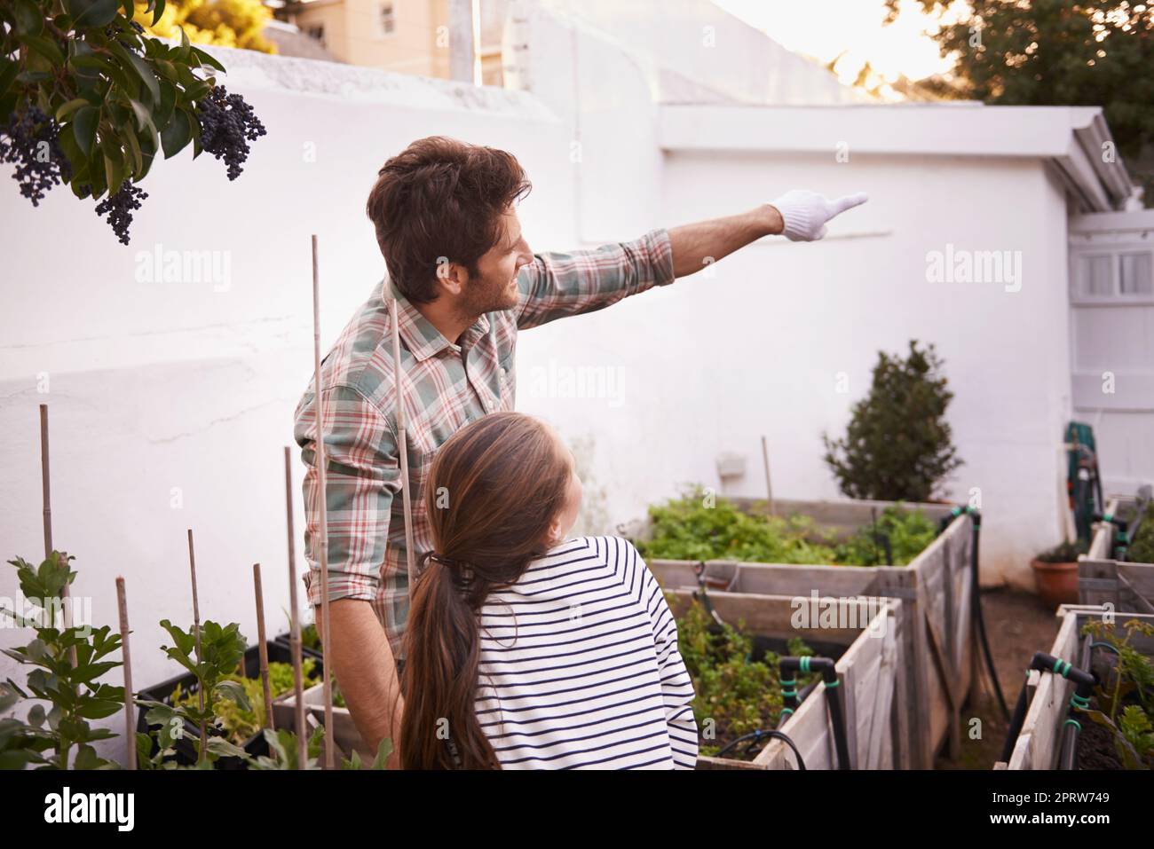 His little girl shares his love for gardening. a father and daughter standing together in their backyard garden. Stock Photo