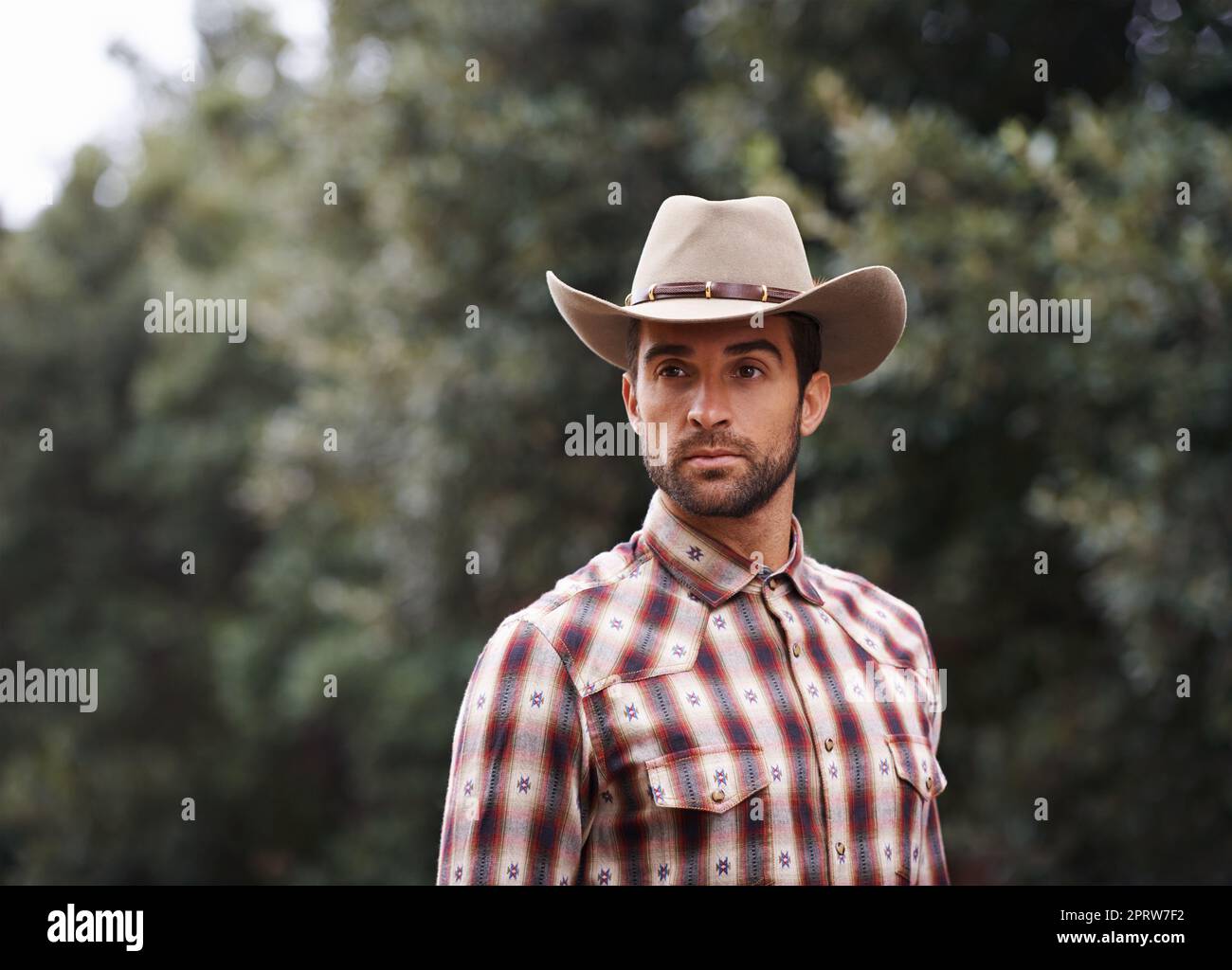 Wild west wrangler. a handsome man wearing a check shirt and cowboy hat. Stock Photo