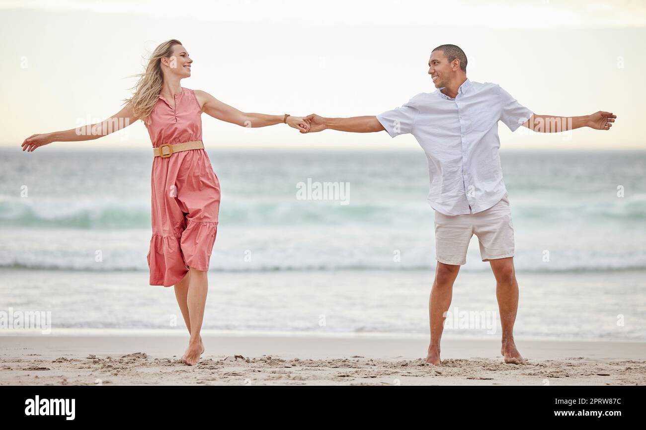 Love, beach and couple happy, smile and romance, care and marriage relationship together. Summer, holiday and happiness with man and woman by the sea on travel vacation trip for freedom or honeymoon Stock Photo