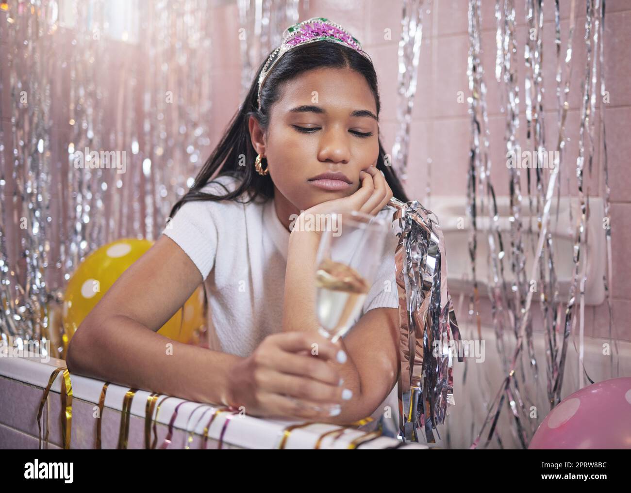Birthday girl, sad and champagne while feeling bored, upset and disappointed while sitting alone in bathtub lonely and depressed. Unhappy, boring and abandoned woman during quarantine celebration Stock Photo