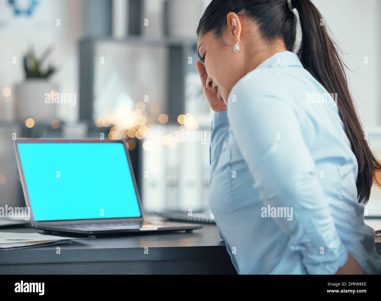 Headache, pain and back injury by business woman working on a laptop, suffering with backache and spine issue. Stress, tension and muscle issue by entrepreneur in distress at work from bad posture Stock Photo