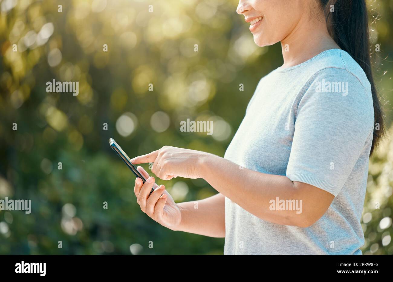 Woman, phone and nature park while touching screen for mobile app, communication for sustainability and environment management tool. Hand of female wi Stock Photo