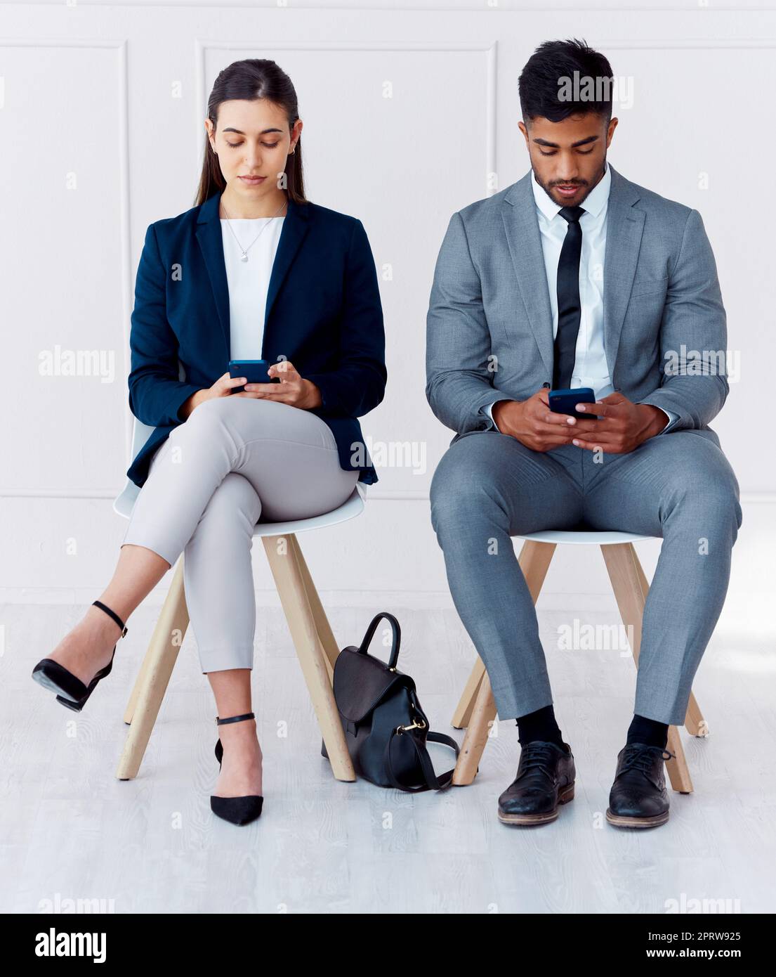 Hiring, interview and phone of businessman and woman with diversity in a office waiting room. Corporate potential workers wait for a company human resources meeting with technology and 5g internet Stock Photo