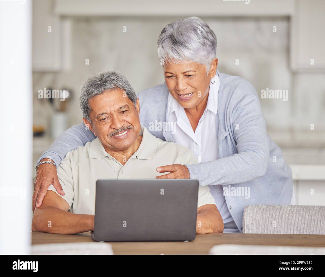 Retirement, laptop and senior couple on the internet reading an email or news via a social network website. Happy elderly woman with a relaxed husband streaming or browsing online at home Stock Photo